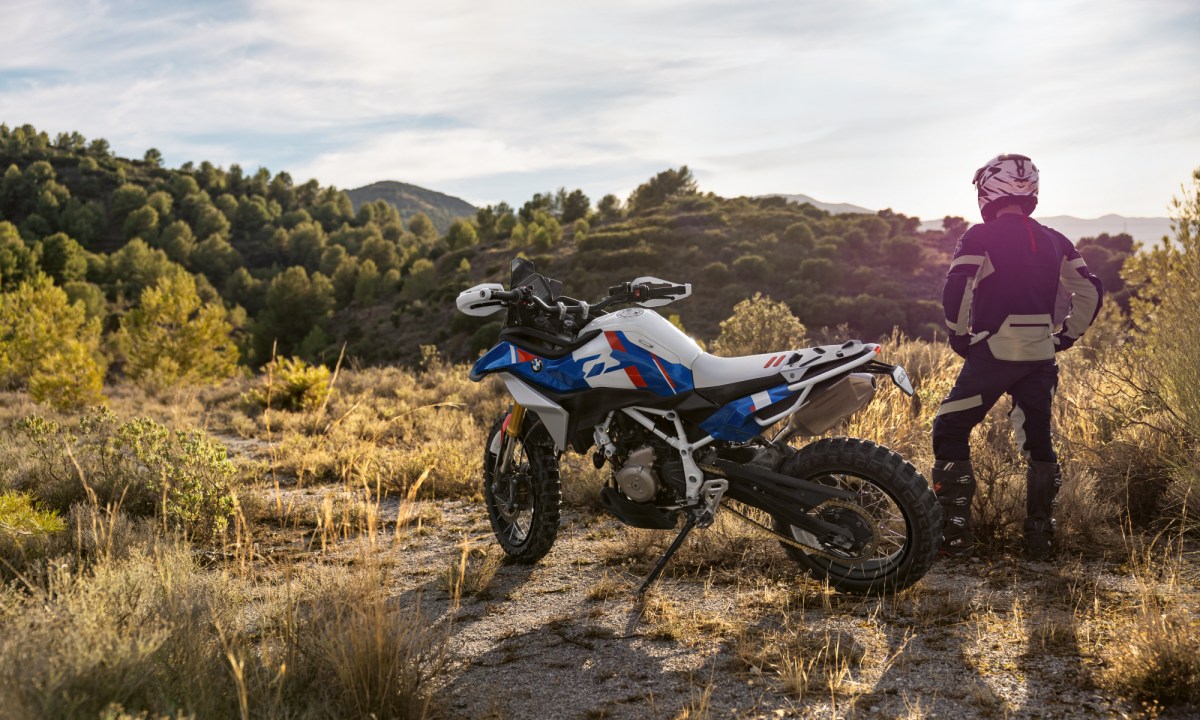 A rider and a BMW Motorrad BMW Concept F 450 GS parked in desert left rear three-quarter view.
