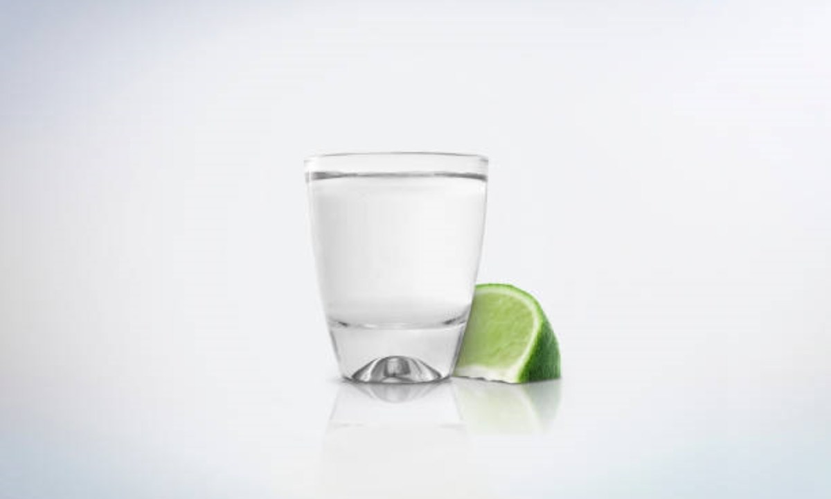 Tequila in shot glass next to a slice of lime