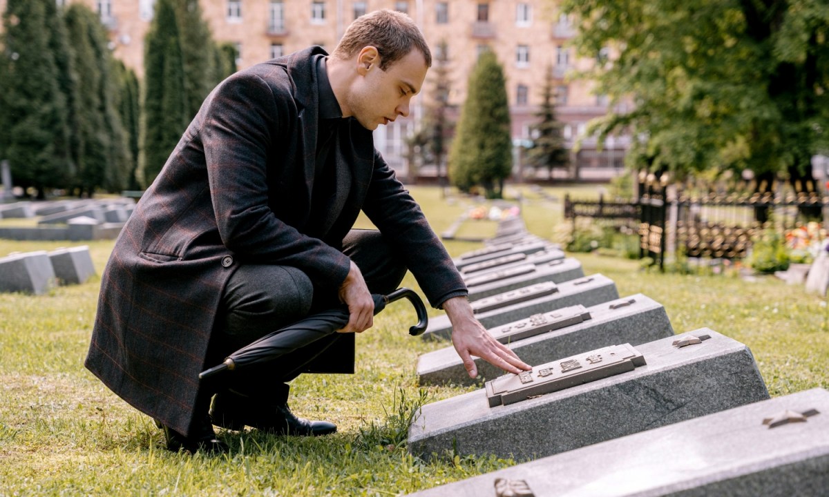 funeral attire for men man kneeling at a grave