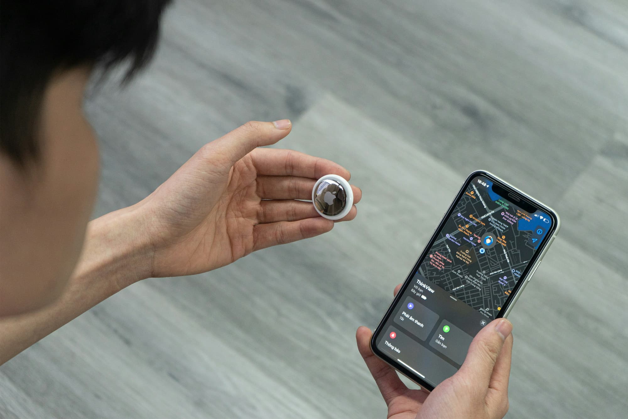 person holding airtag and smartphone