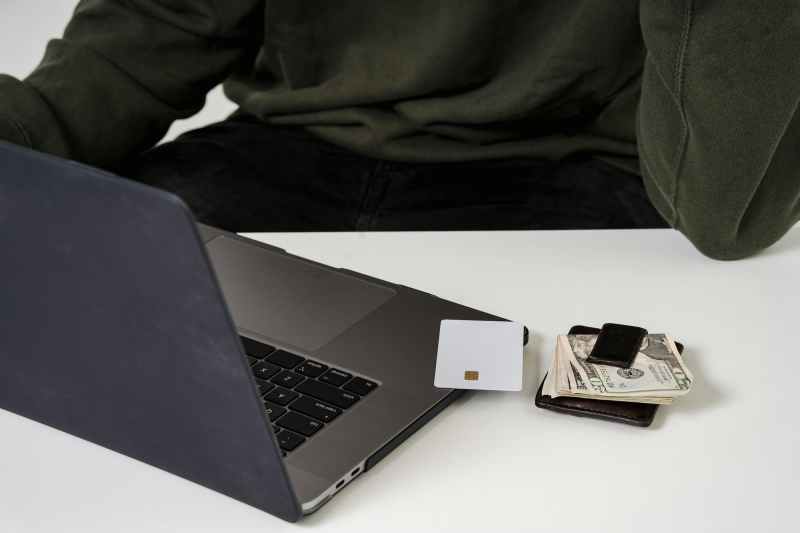 computer on table with credit card and wallet next to it