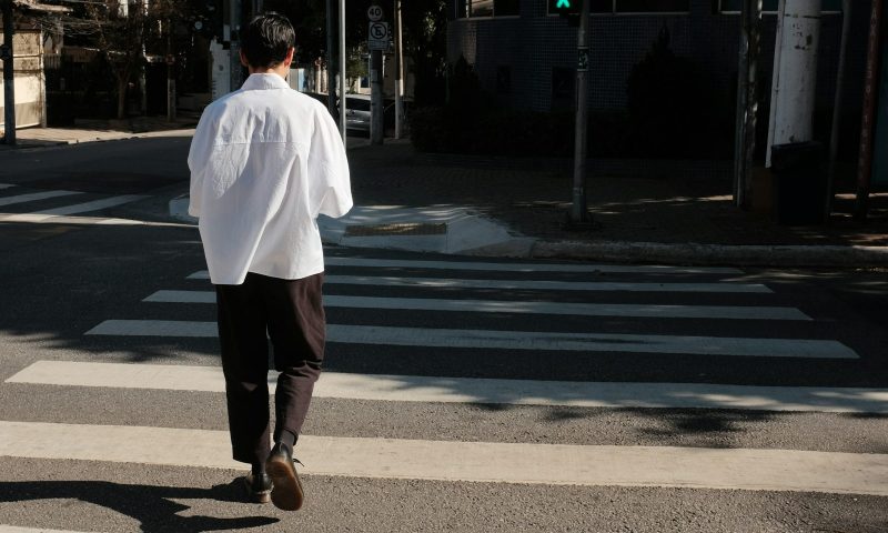 man walking around the block across the street crosswalk