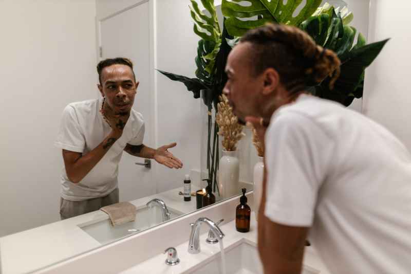 young man looking in mirror at skin