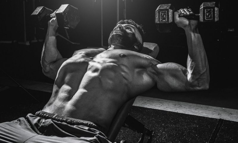 shirtless man lifting weights dumbbells