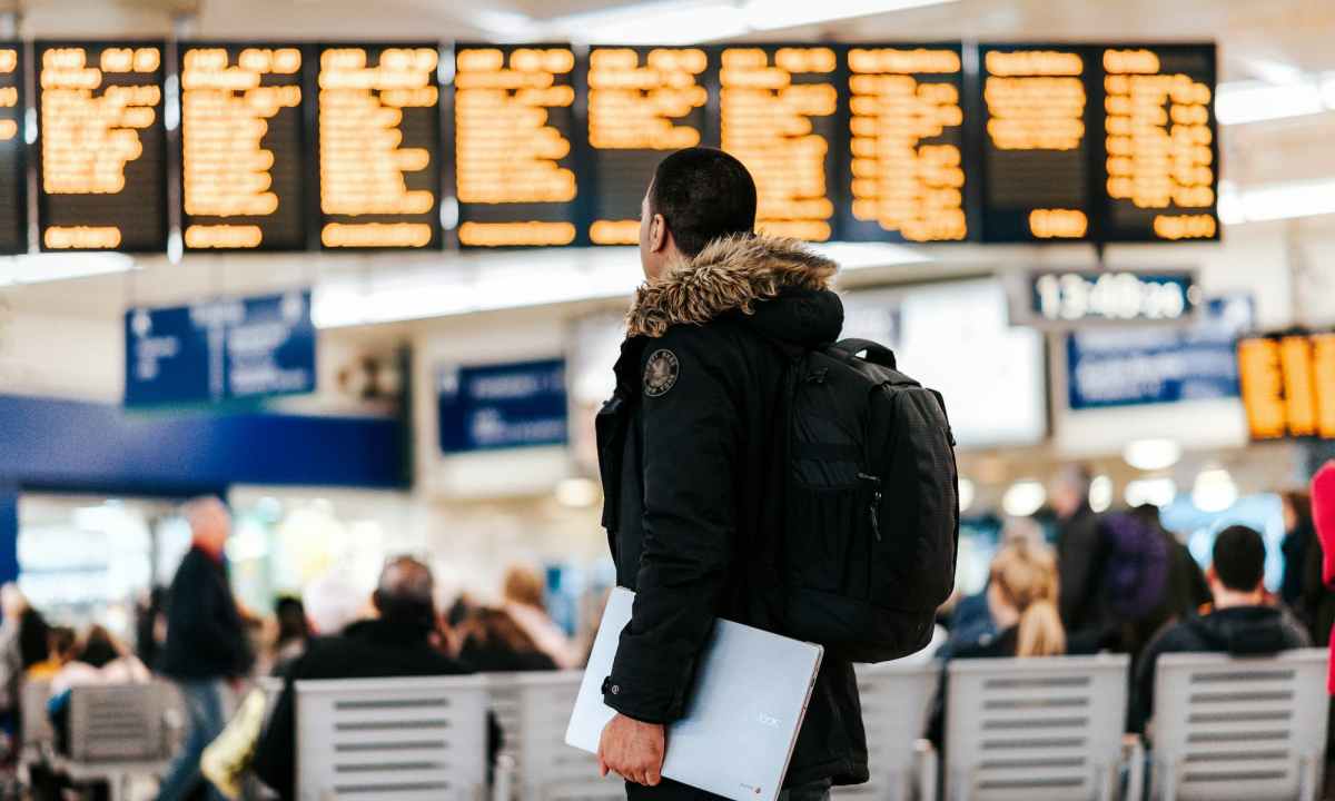 Man standing in airport looking at flight schedule