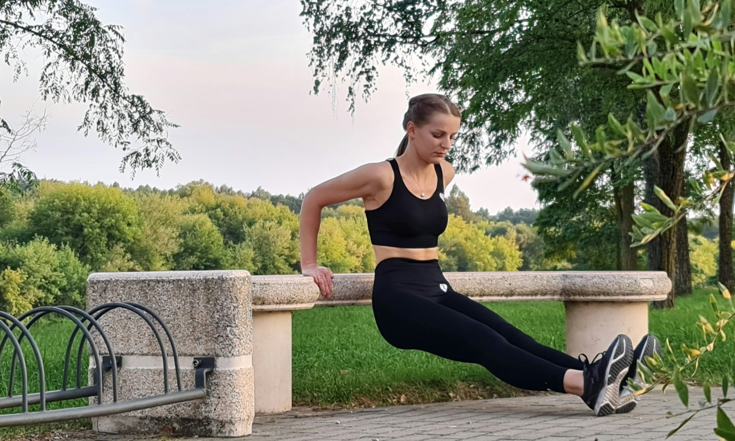 Woman doing bench dips outside by trees