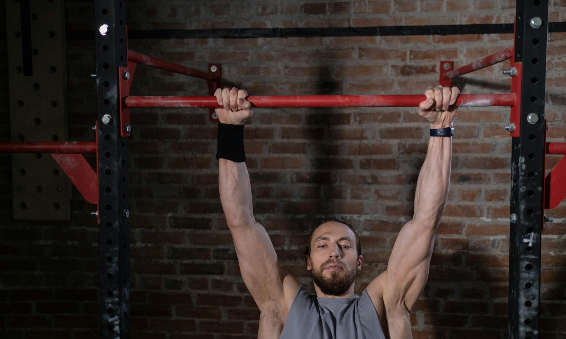 man hanging from pull up bar dead hang pull up exercise strong arms