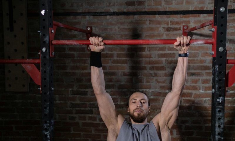 man hanging from pull up bar dead hang pull up exercise strong arms