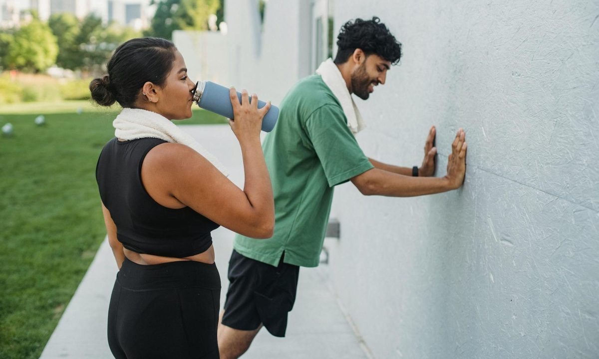 man and woman working out taking break drinking sports drink exercise stretch
