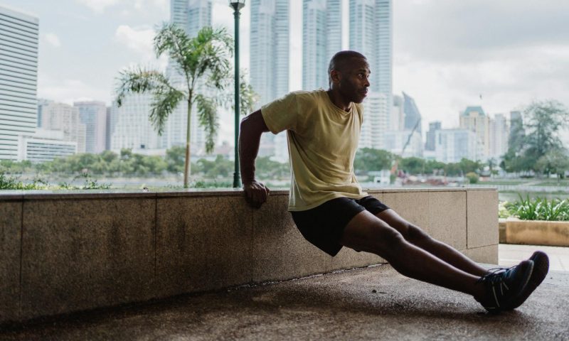 Man doing bench triceps dips outside
