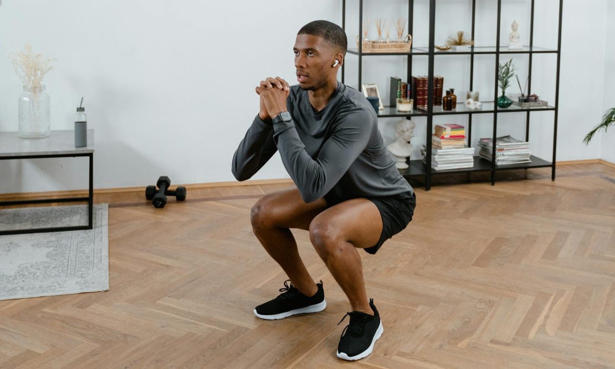 Man squatting down doing jump squats at home workout
