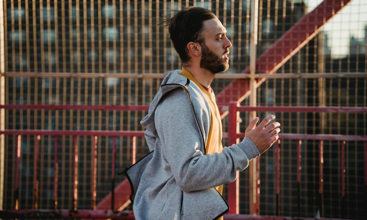 man running wearing hoodie outside two shirts