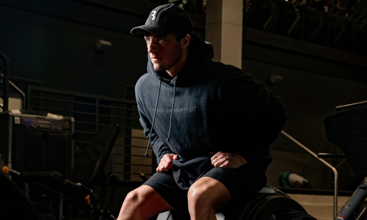 man wearing hoodie sitting on gym machine workout exercise