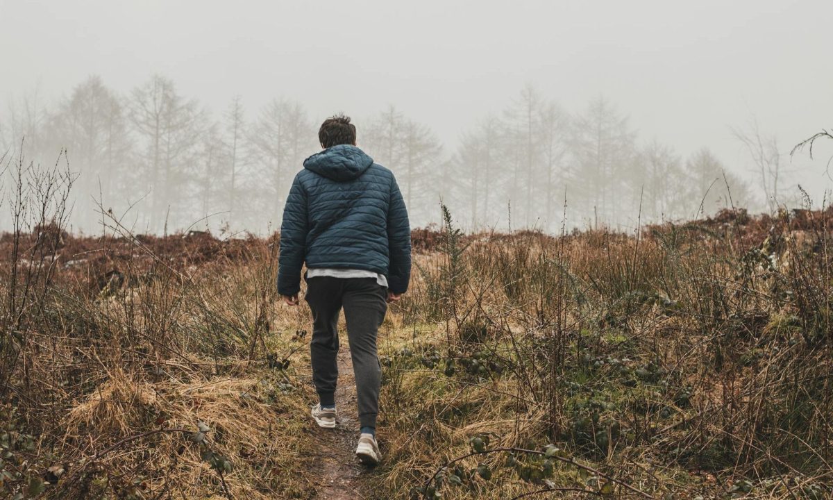 Man walking outside with coat in nature