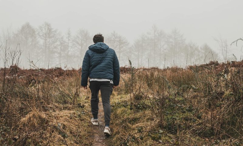 Man walking outside with coat in nature