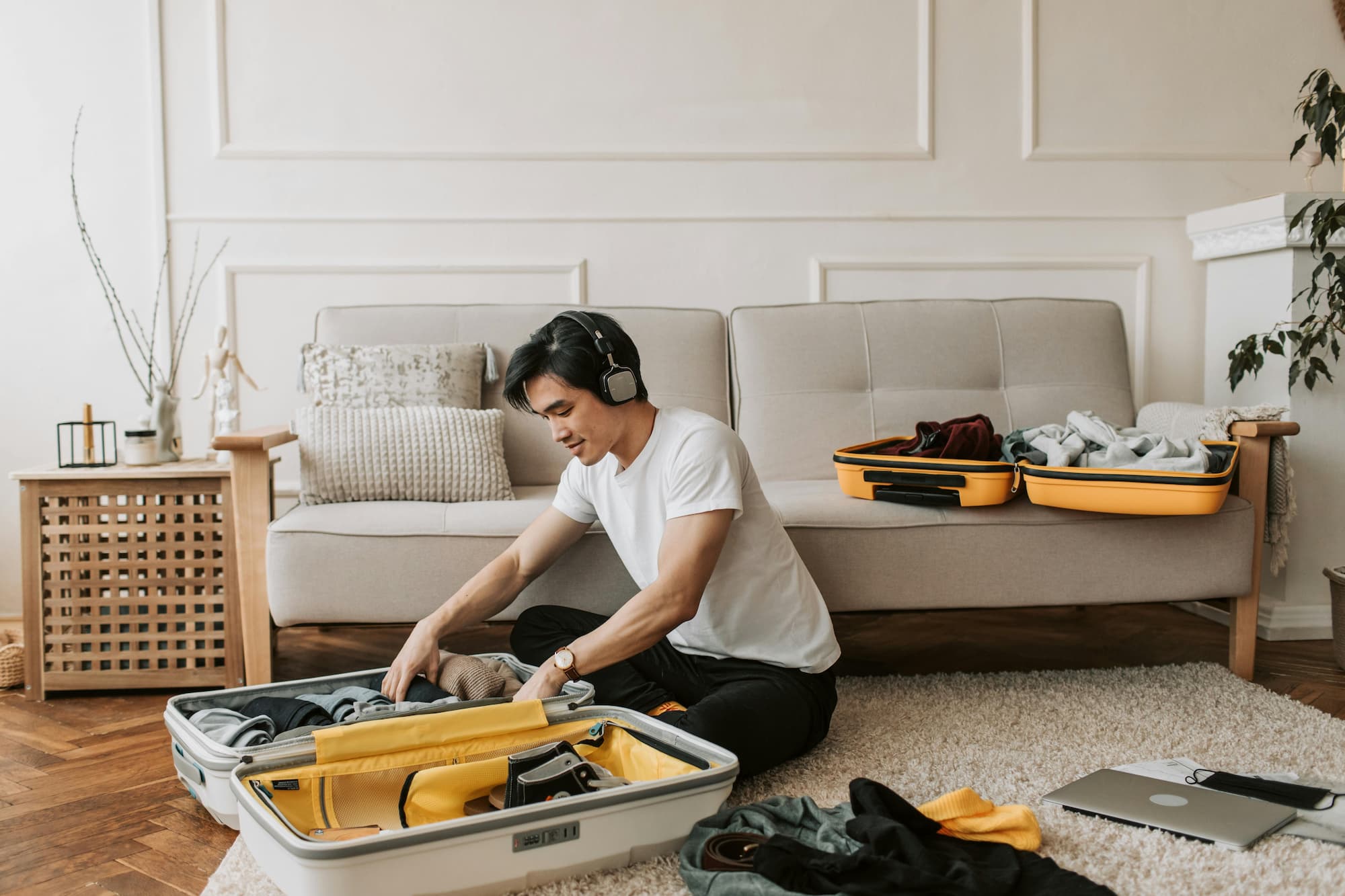 a man wearing headphones while packing clothes in a suitcase