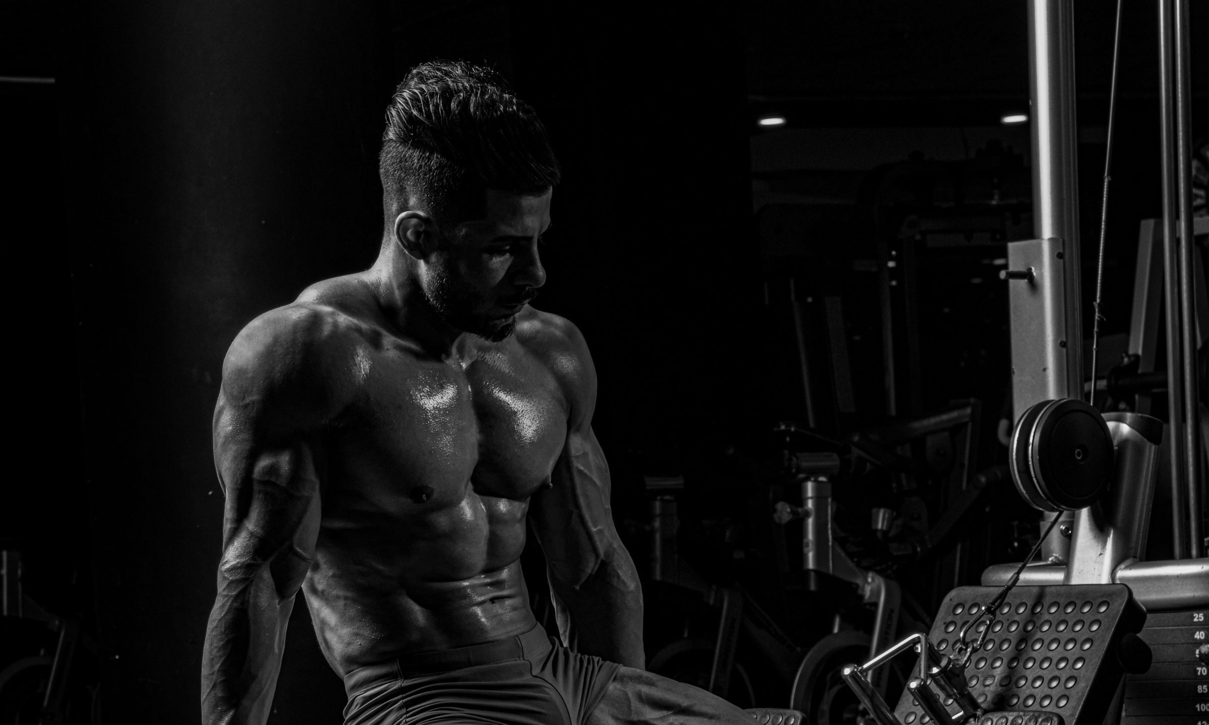 man sitting on bench black and white image abs muscular muscles gym
