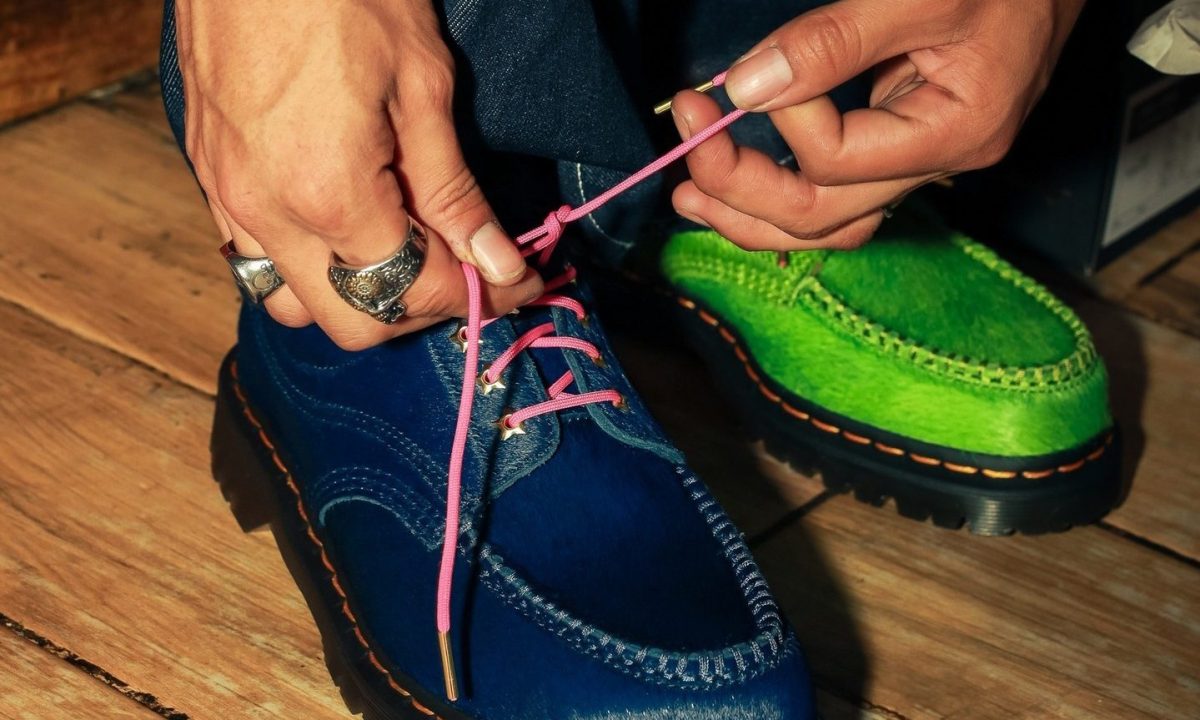 man tying blue and green dr marten shoes