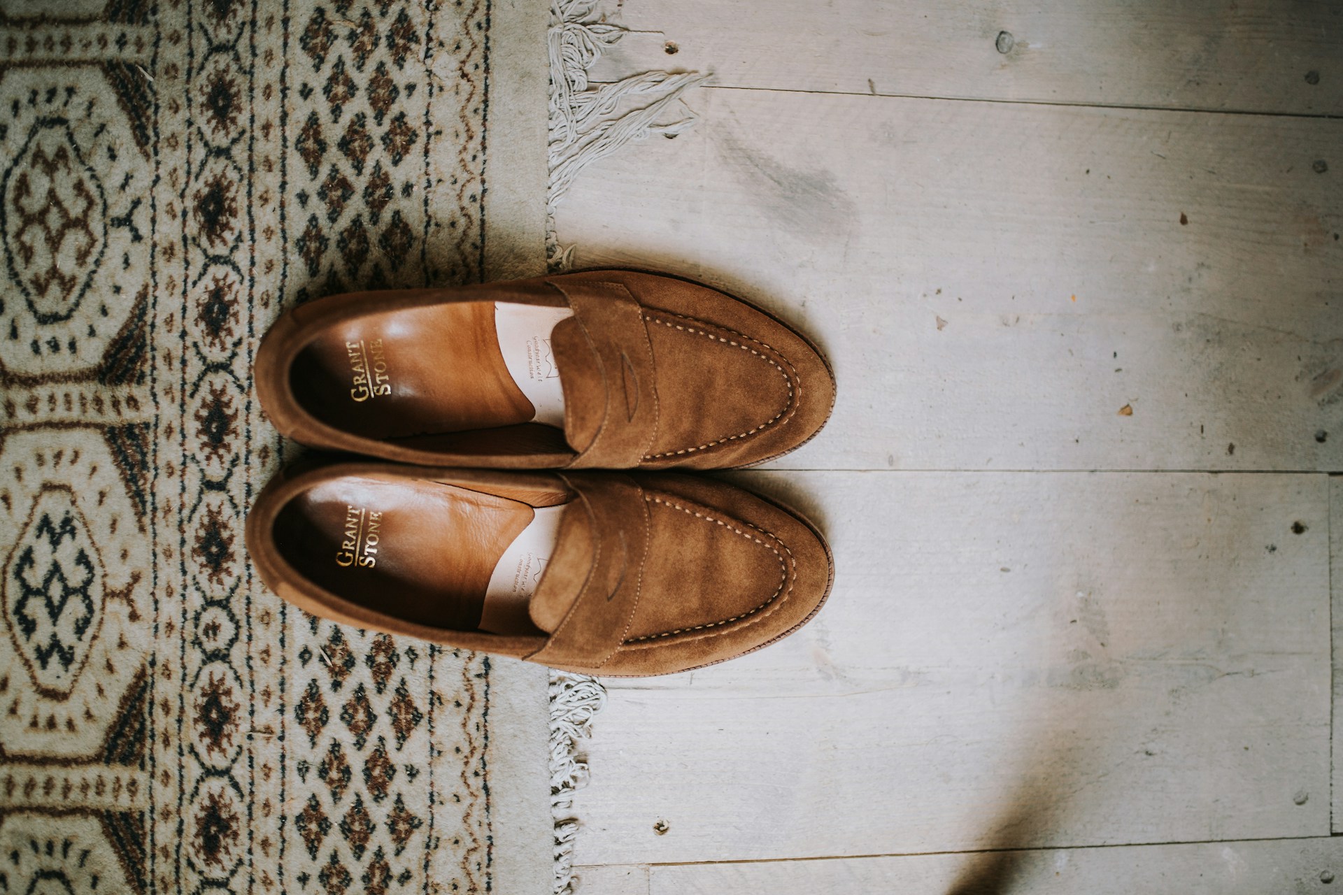 Brown suede penny loafers on floor