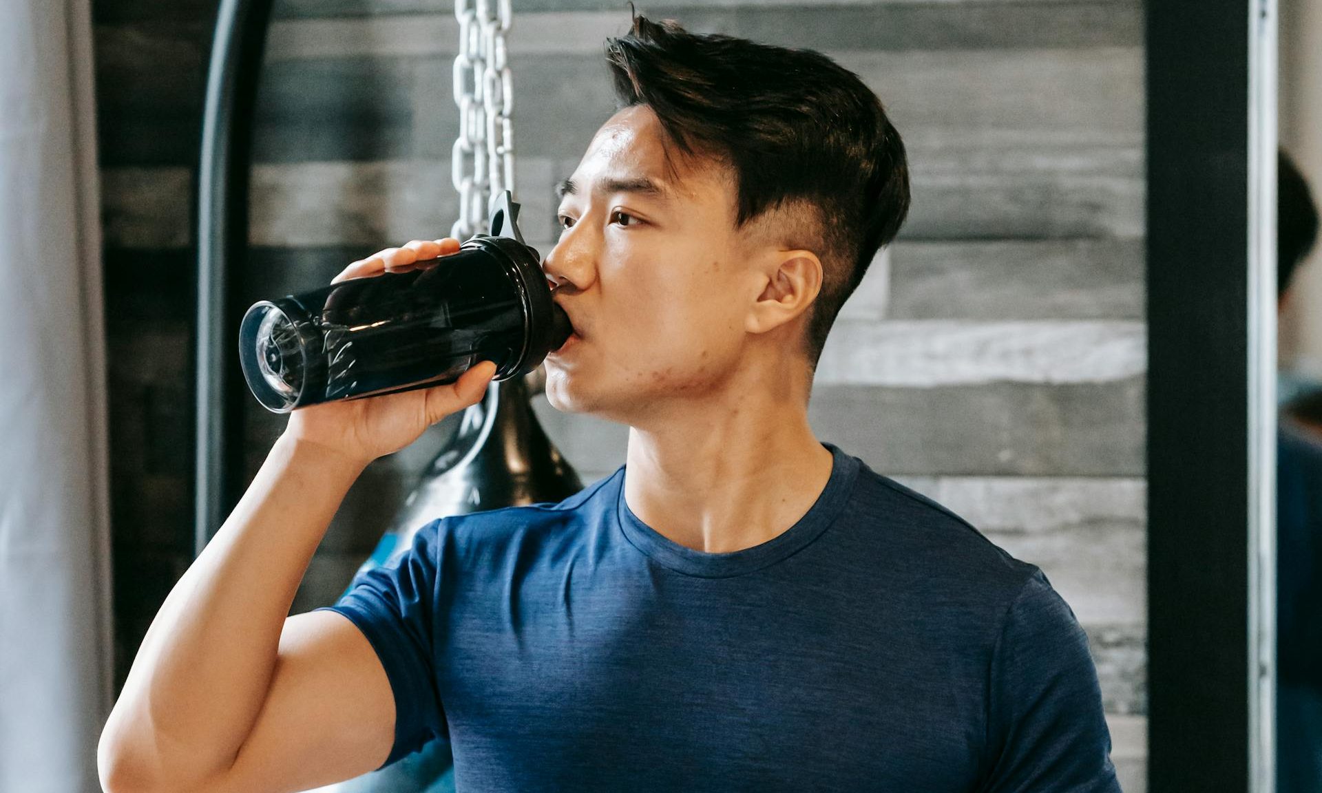 Man in gym taking supplement drinking protein shake powder electrolyte mineral