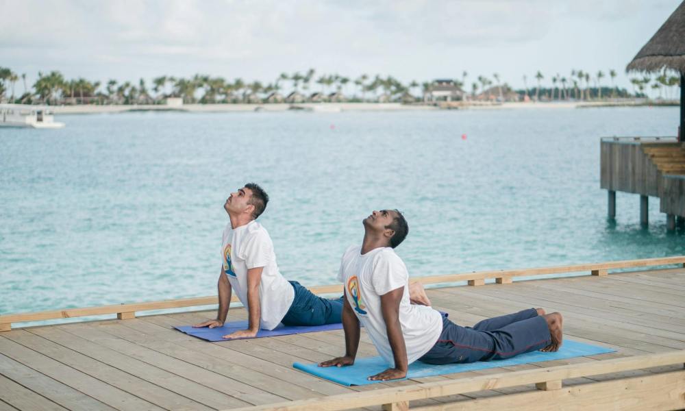 two men doing yoga on a pier water outdoors
