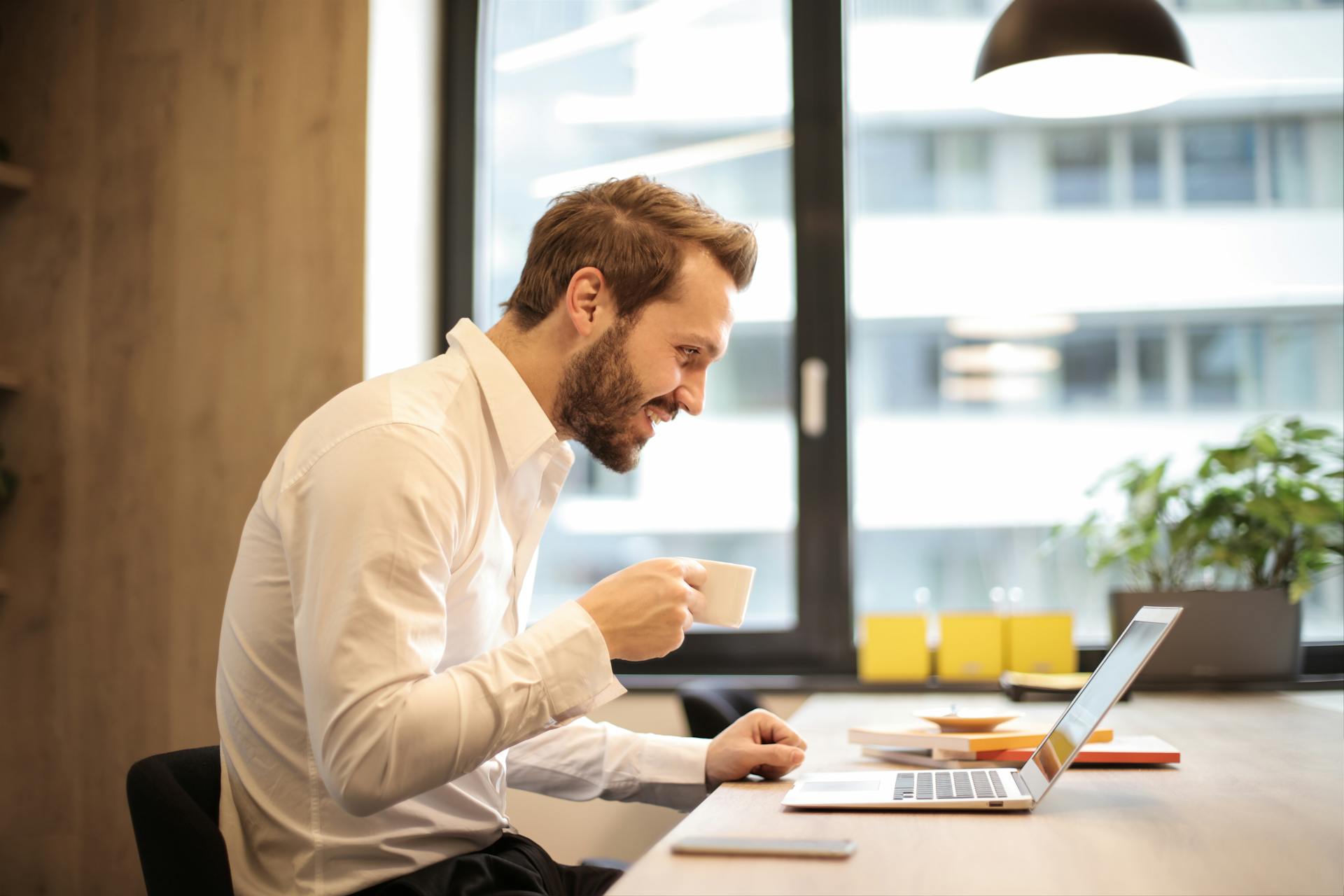 Man drinking coffee while working on a laptop