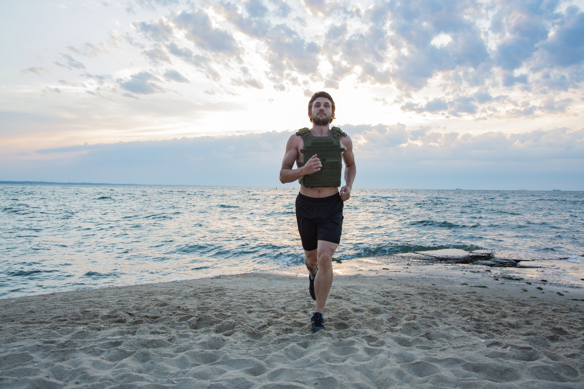 man walking jogging running wearing weighted vest outdoors beach workout