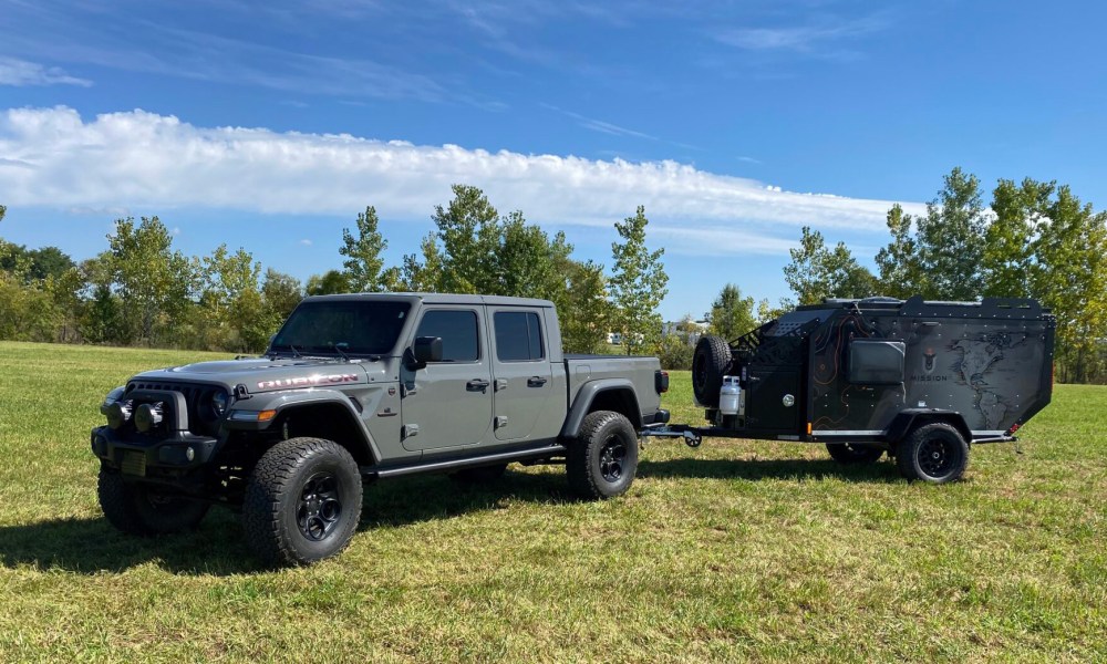 Mission Overland Trail Dog powersports towable camper parked in a field.