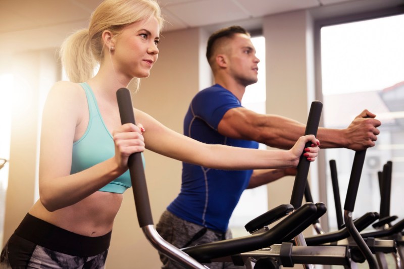 Man and woman using ellipticals