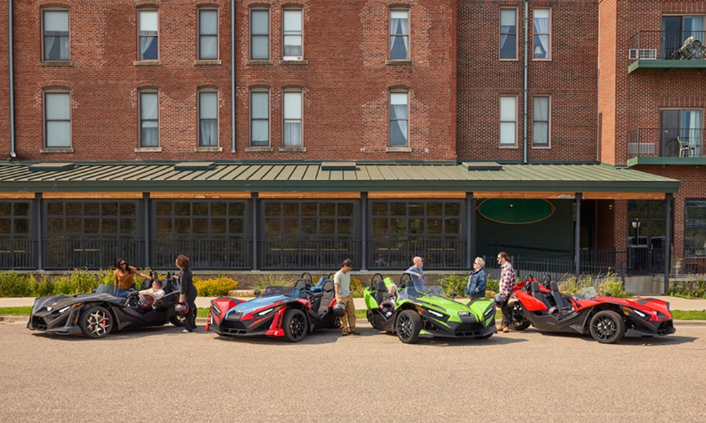 2025 Polaris Slingshot lienup parked in front of an apartment building, models S, SL, SLR, and R.