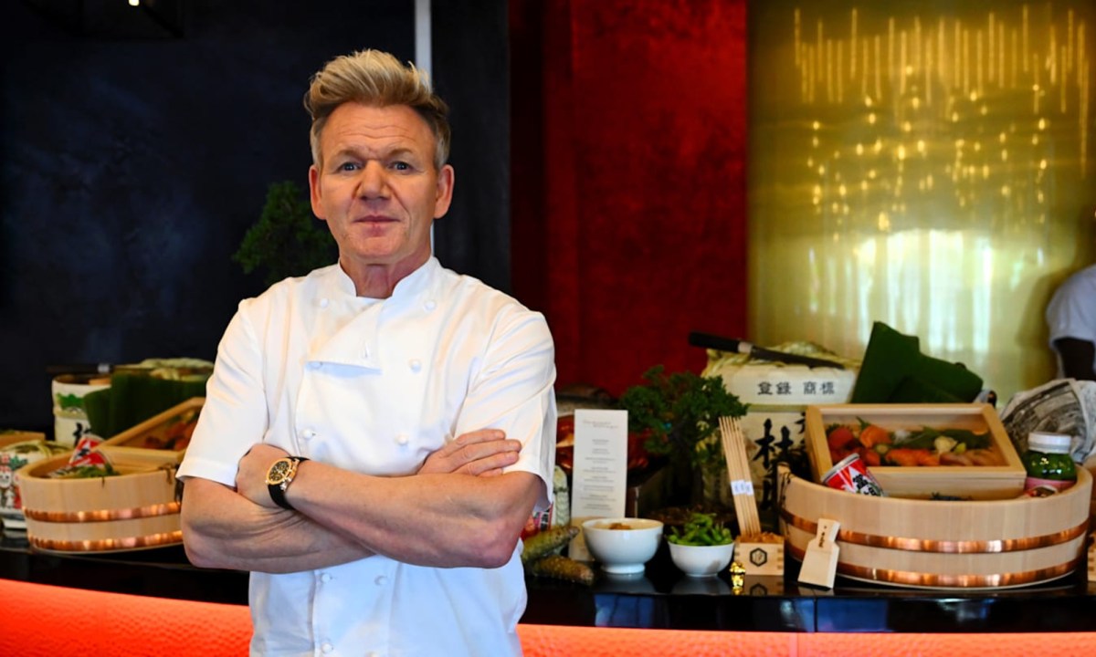 Gordon Ramsay stands in front of a food table at Pit Garage.