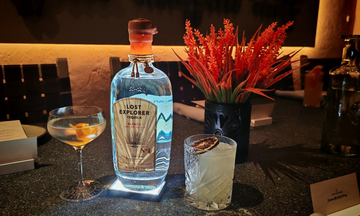A bottle of The Lost Explorer alongside two cocktails