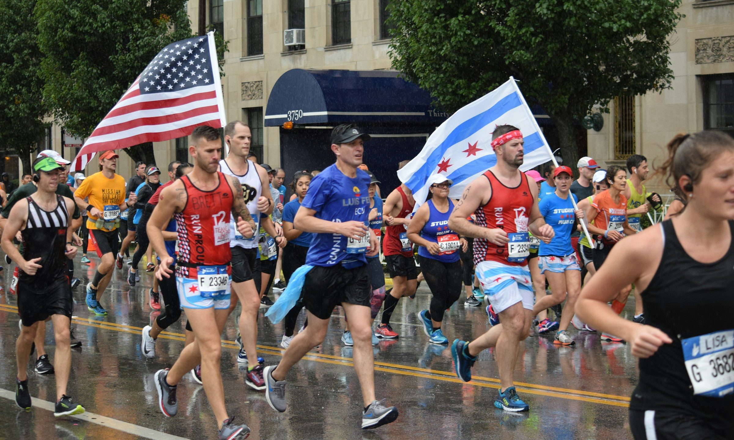 men running in marathon with US flag rainy