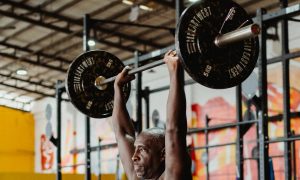 man lifting overhead barbell press in gym