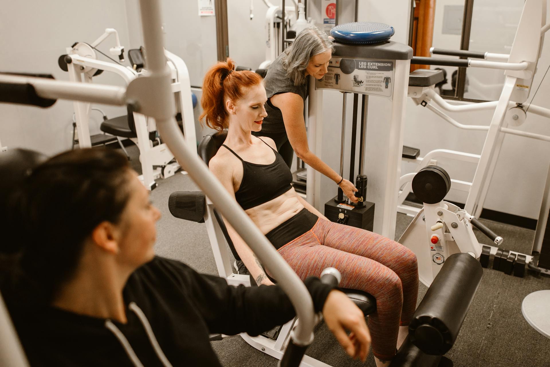 two women working out gym leg press knee extension