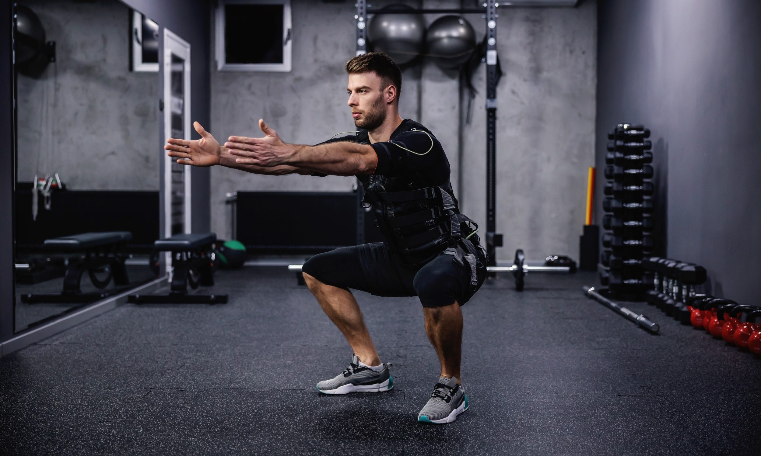 Man squatting with EMS suit on work out exercise
