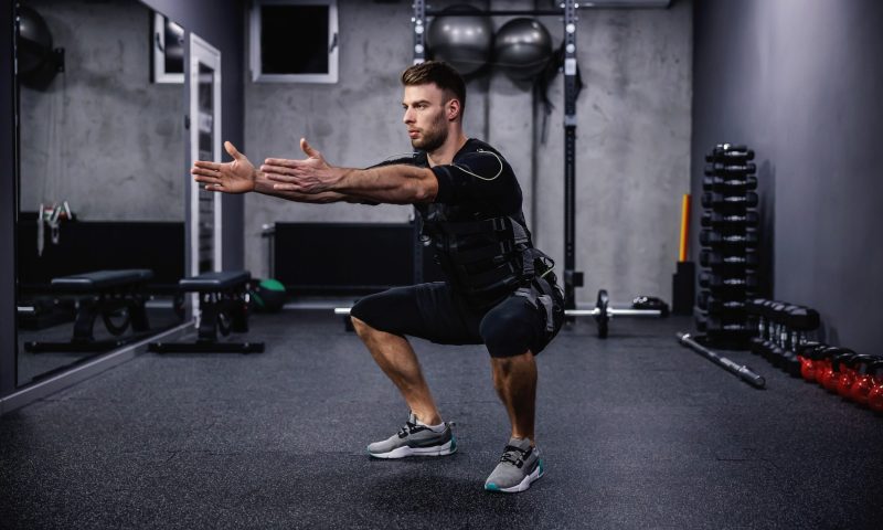 Man squatting with EMS suit on work out exercise