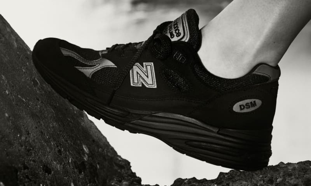model in black new balance standing on rock