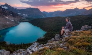 A man hiking to a beautiful view of a lake at sunset
