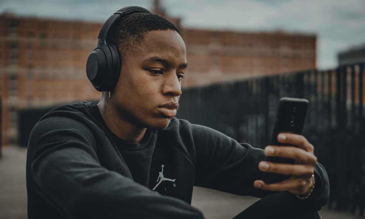 Man with headphones on looking at his phone