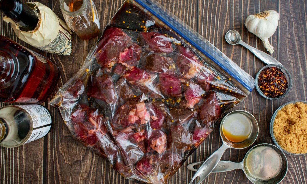 Marinating raw steak tips in a plastic bag