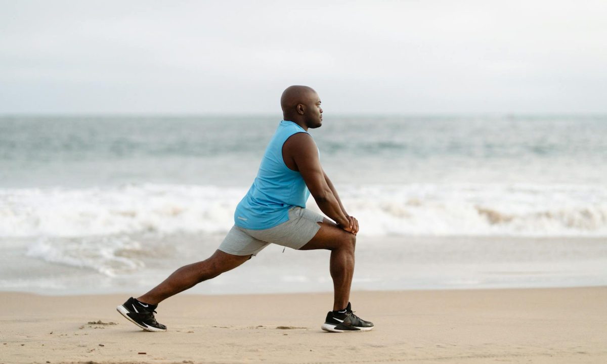 Man on vacation exercising stretching legs on a beach