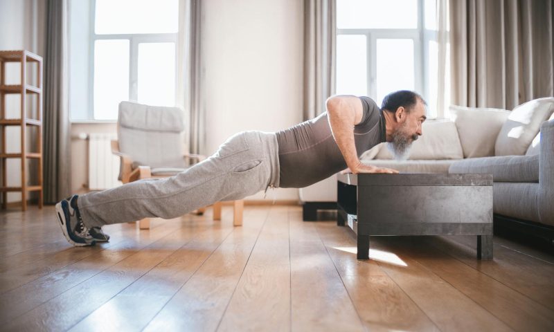 man exercising older man doing push ups workout inside home