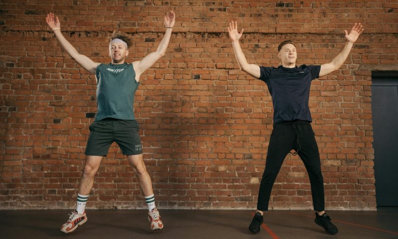 two men doing jumping jacks jumping working out