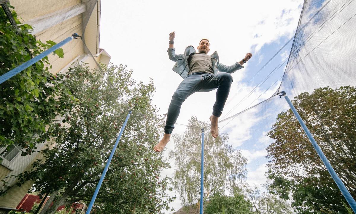 man jumping on trampoline rebounder