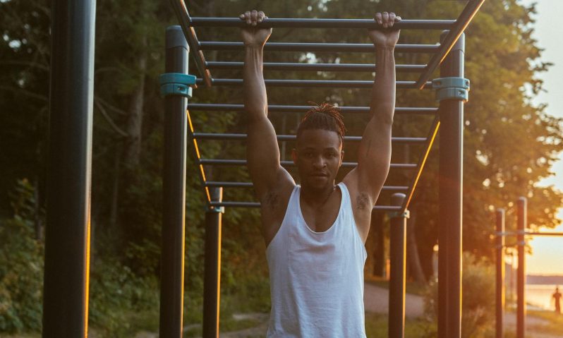 man pull -up dead hang outside training sunset