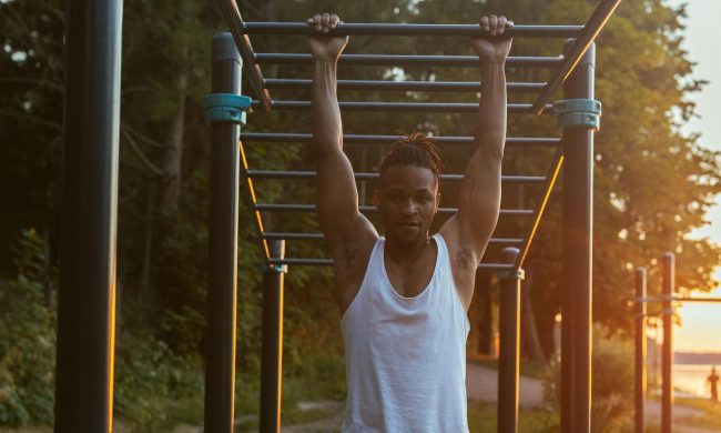 man pullup dead hang outdoor workout sunset