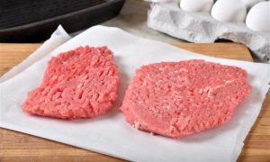 Two uncooked cubed steaks on a cutting board