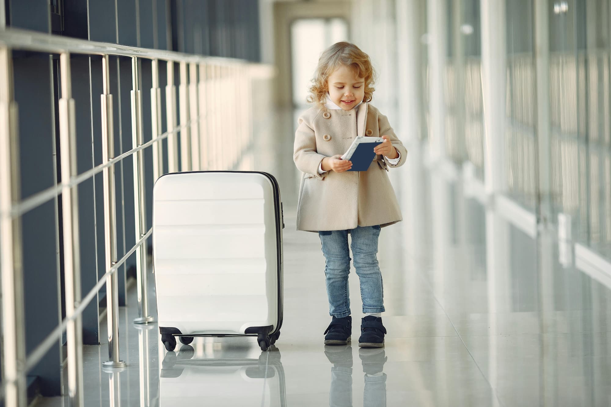 little girl standing next to suitcase in airport