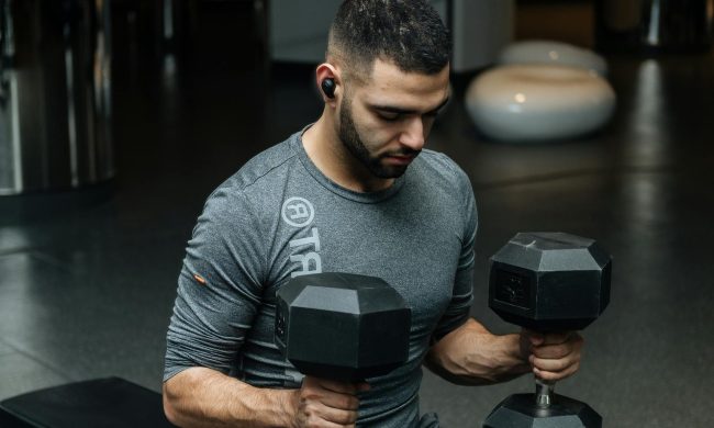man holding two dumbbells on bench